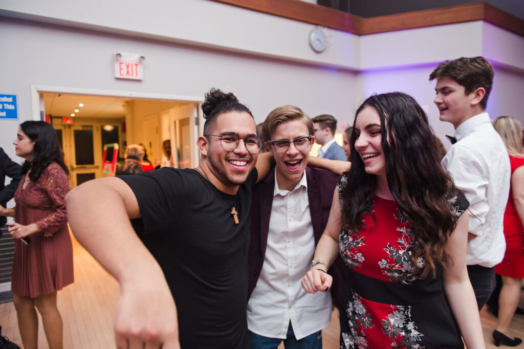 Three people laughing and standing with their arms around each other.